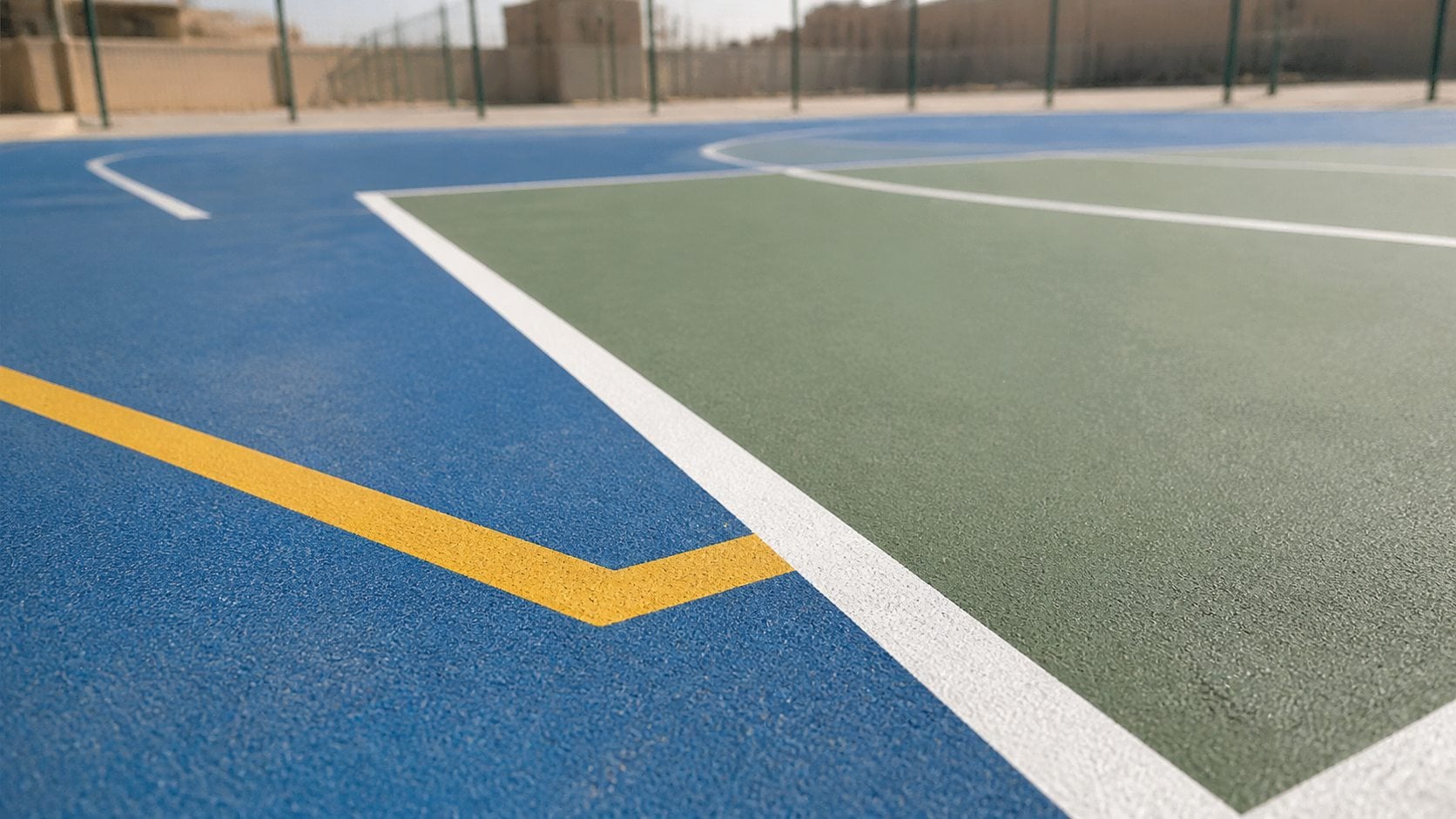 Outdoor acrylic sports court surface with blue green areas and crisp line markings in Saudi Arabia